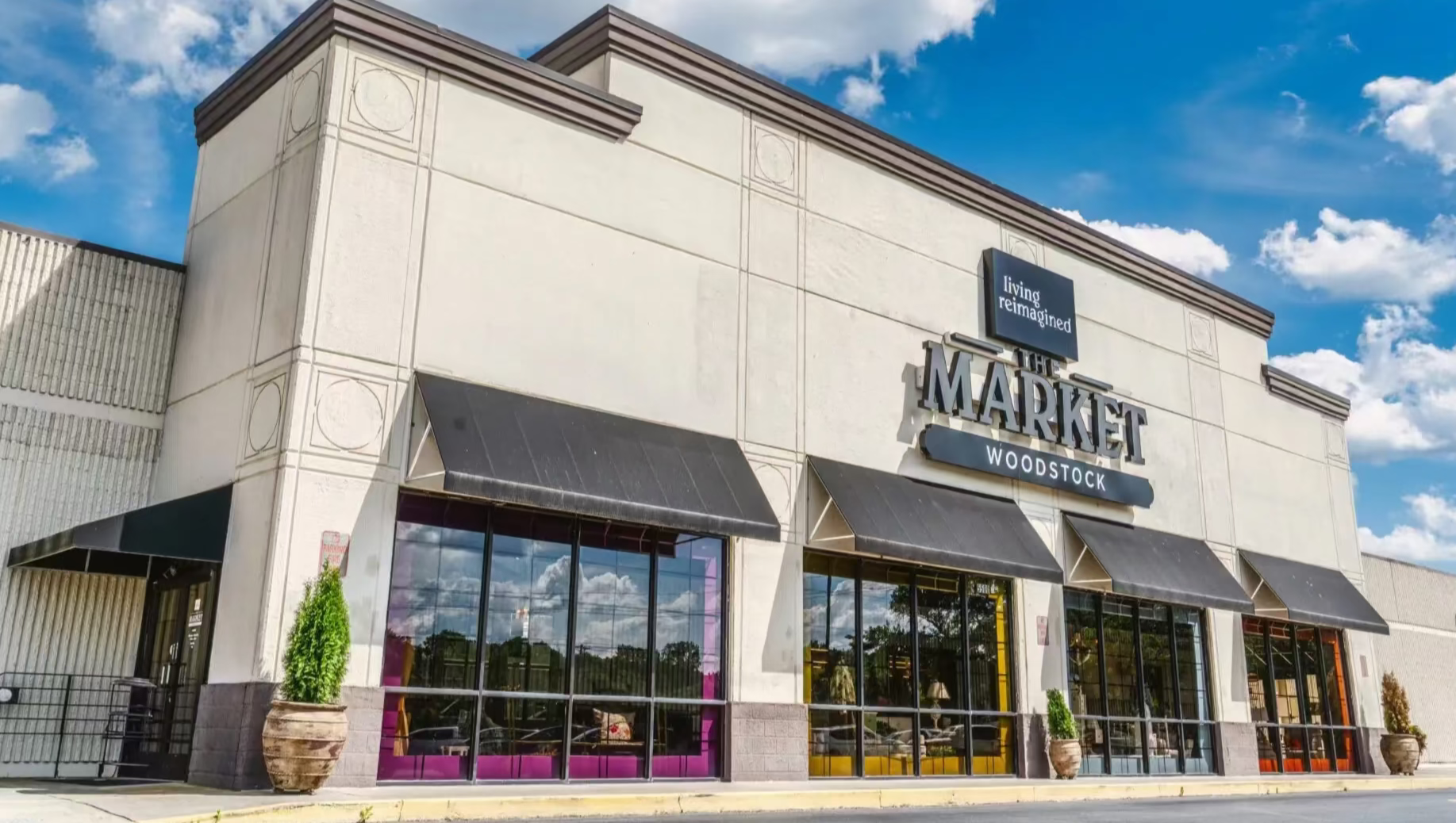 Storefront with 'The Market Woodstock' sign under a blue sky with clouds.